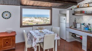 Una cucina con vista sul mare, un tavolo da pranzo con sedie e un frigorifero.