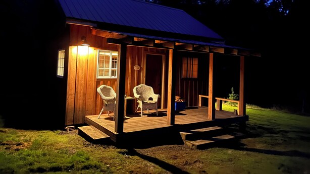 A wooden cabin with a porch, two wicker chairs, and a small table. - Tranquil cabin with WiFi in Brush Prairie (Brush Prairie)