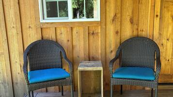 A wooden porch with two wicker chairs and a small table.