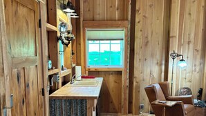 A wooden cabin interior with a kitchen area, a rocking chair, and a window with blinds. - Tranquil cabin with WiFi in Brush Prairie (Brush Prairie)