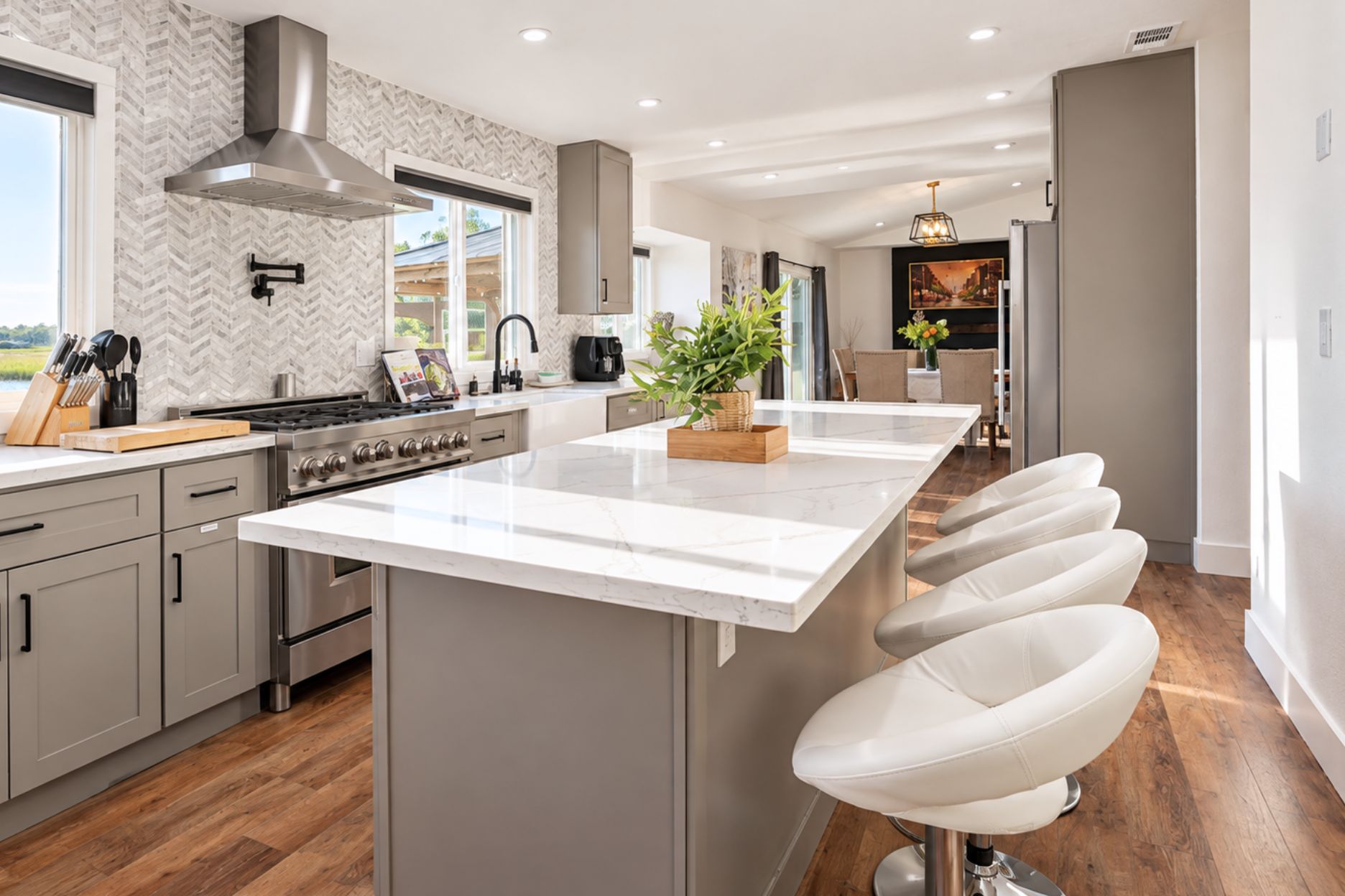 Et moderne køkken med en stor ø, rustfrie stålgre og et backsplash med et nyancemønster.