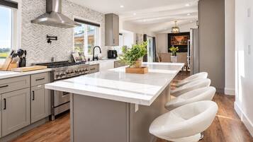 Et moderne køkken med en stor ø, rustfrie stålgre og et backsplash med et nyancemønster.