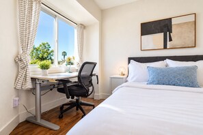A hotel room with a bed, a desk, and a chair.