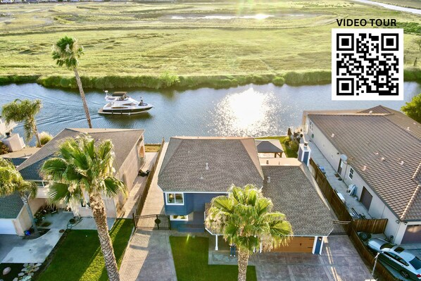 Ein Wohngebiet mit Häusern, einem Boot auf dem Wasser und einem QR-Code für eine Video-Tour.