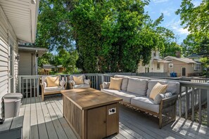 A wooden deck with a sofa, chairs, and a coffee table.