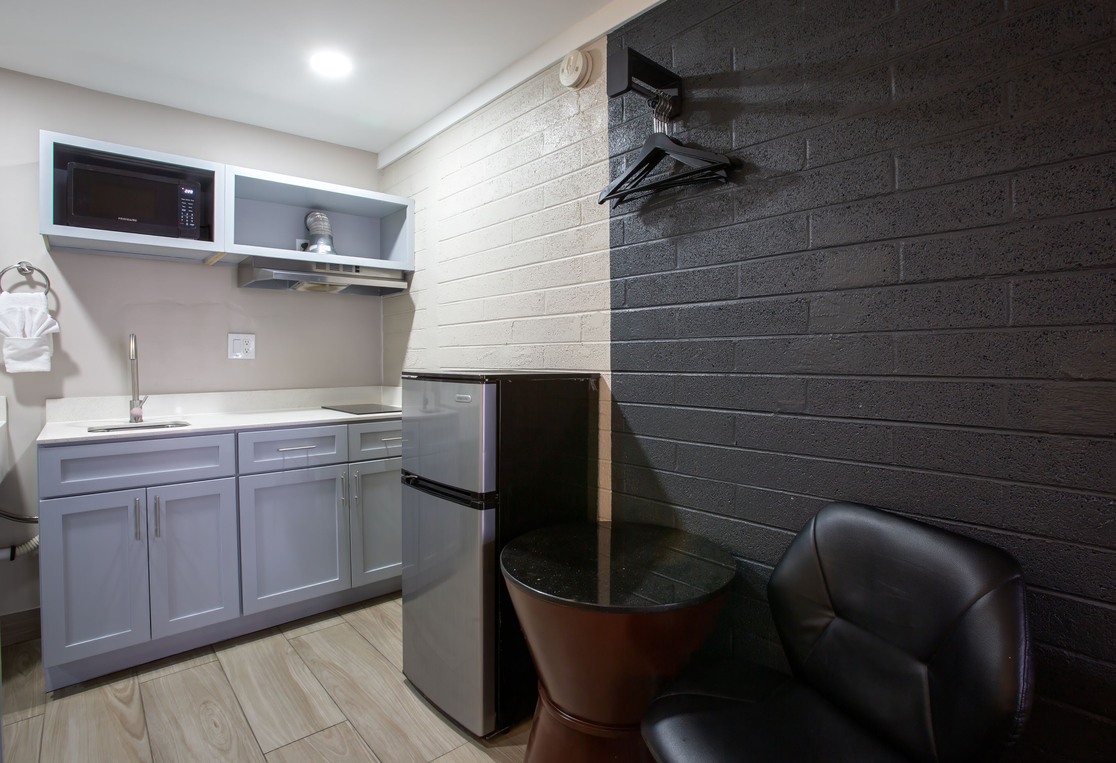 Una cocina moderna con microondas integrado, refrigerador de acero inoxidable y encimera negra.