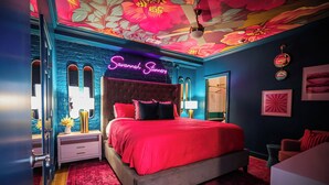 A bedroom with a neon sign reading "Savannah Turner," a tufted headboard, red bedding, and a floral ceiling design. - 9 beauty bars, Photo booth, Karaoke-Girls Getaway steps away from River Street (Savannah)