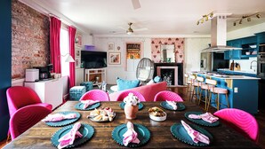 A dining area with a wooden table set for a meal, surrounded by vibrant chairs. - 9 beauty bars, Photo booth, Karaoke-Girls Getaway steps away from River Street (Savannah)