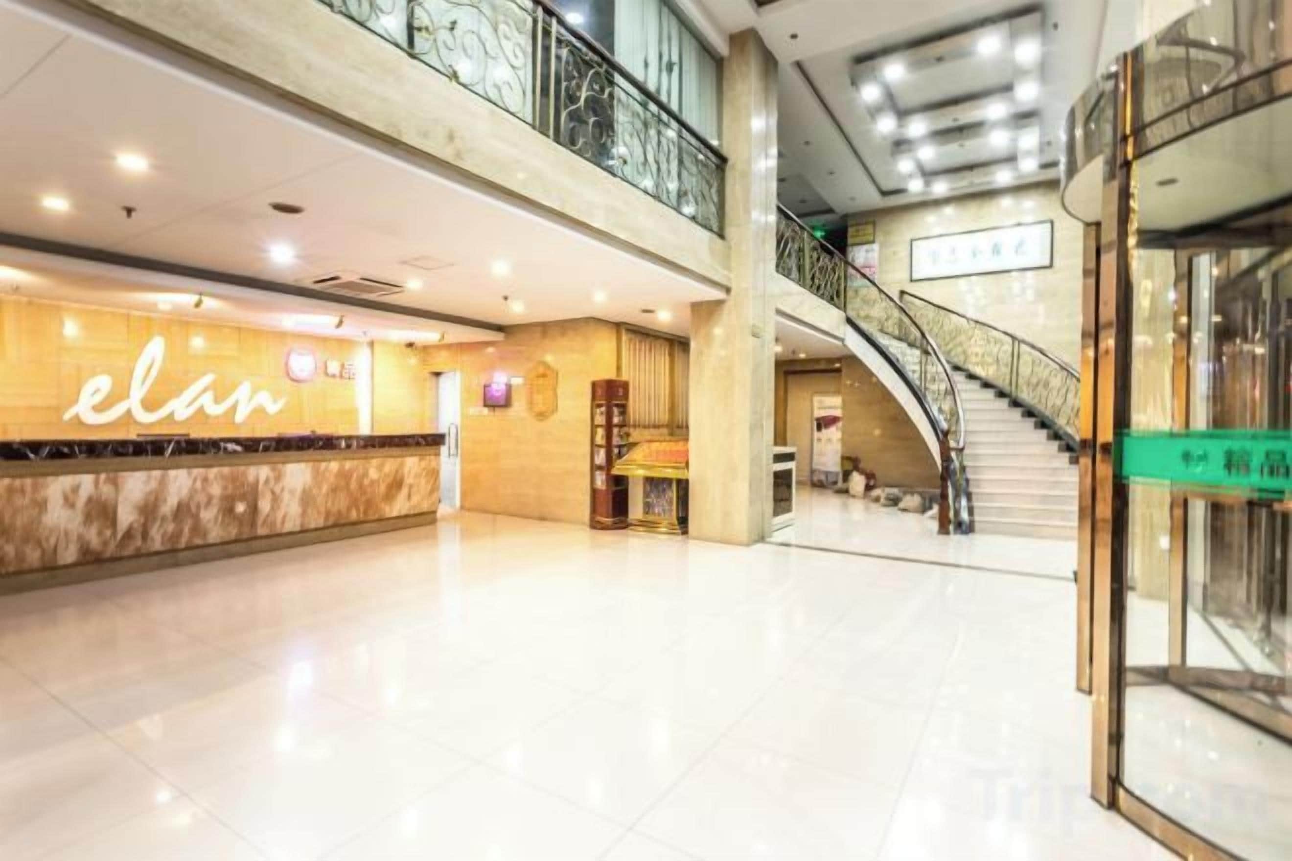 A spacious indoor area with a reception desk, a staircase, and a glass storefront.