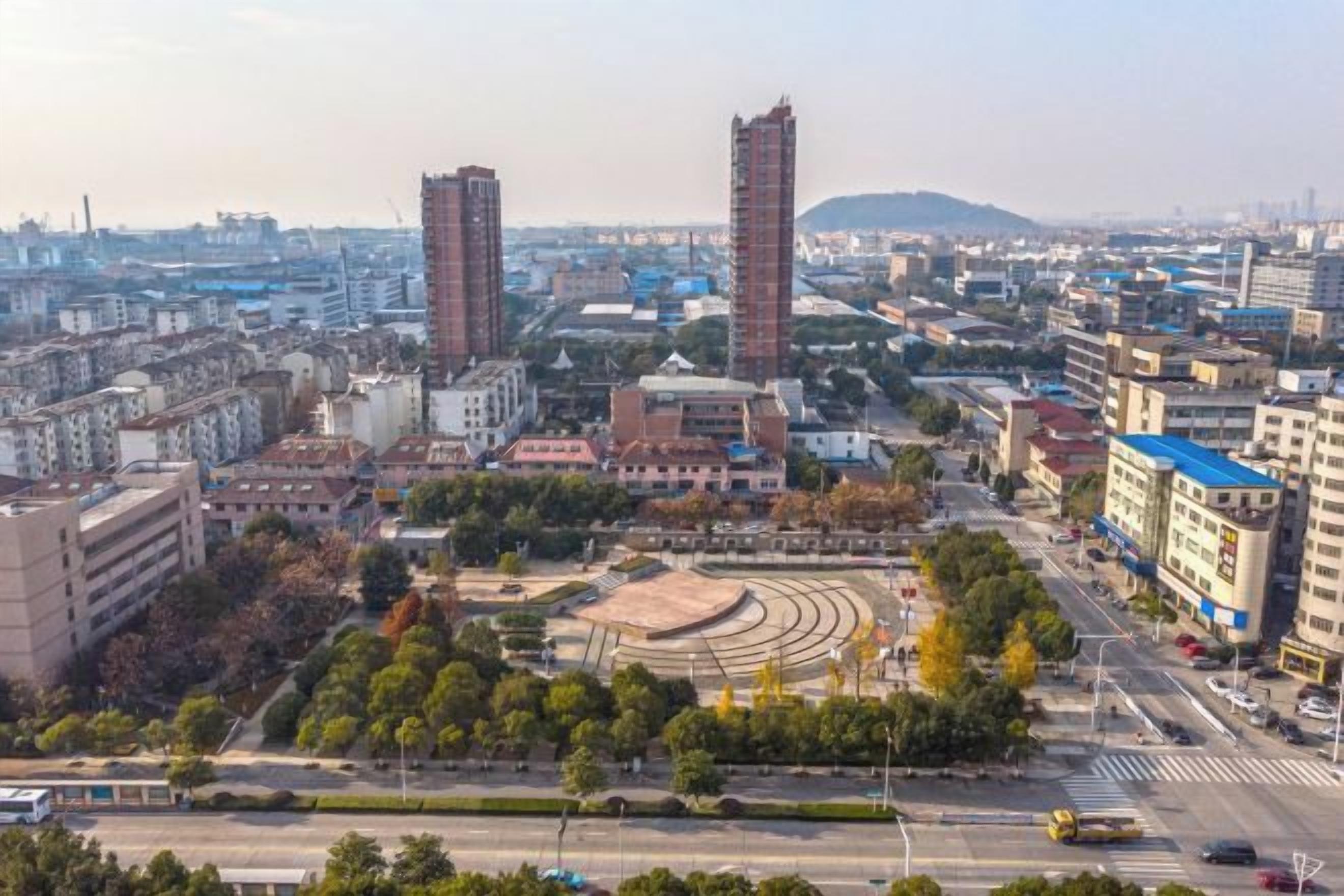 A cityscape with multiple high-rise buildings, a roundabout, and a mix of commercial and residential structures.