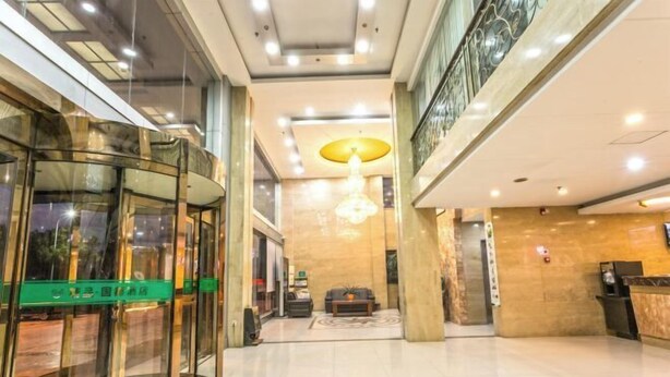 A hotel lobby with a glass elevator, a reception desk, and a chandelier. - Boutique Guodu Hotel (Nantong)