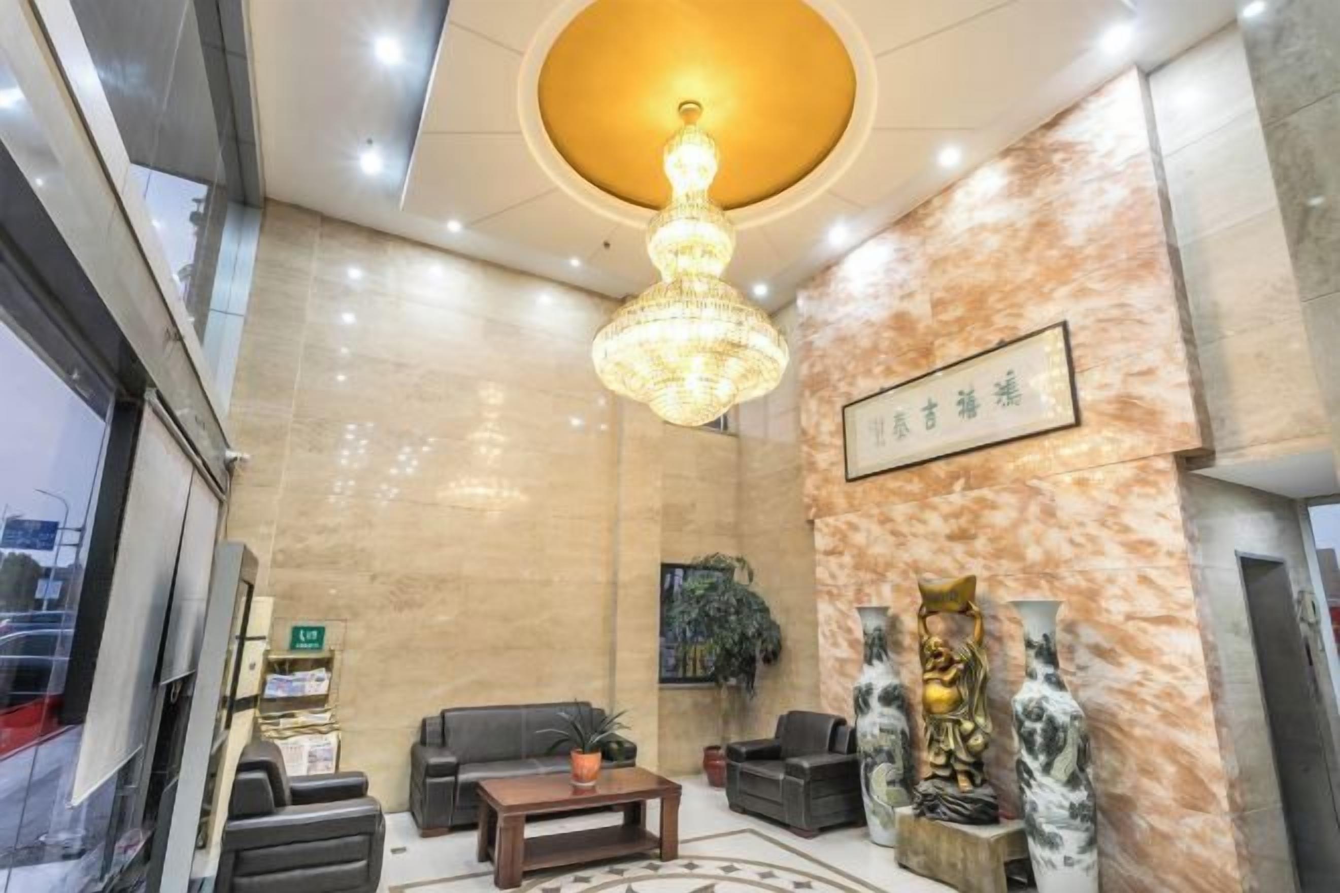 A lobby with a chandelier, sofas, a coffee table, and decorative vases.