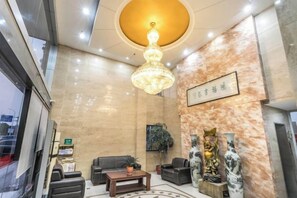 Eine Lobby mit einem Kronleuchter, Sofas, einem Couchtisch und dekorativen Vasen.