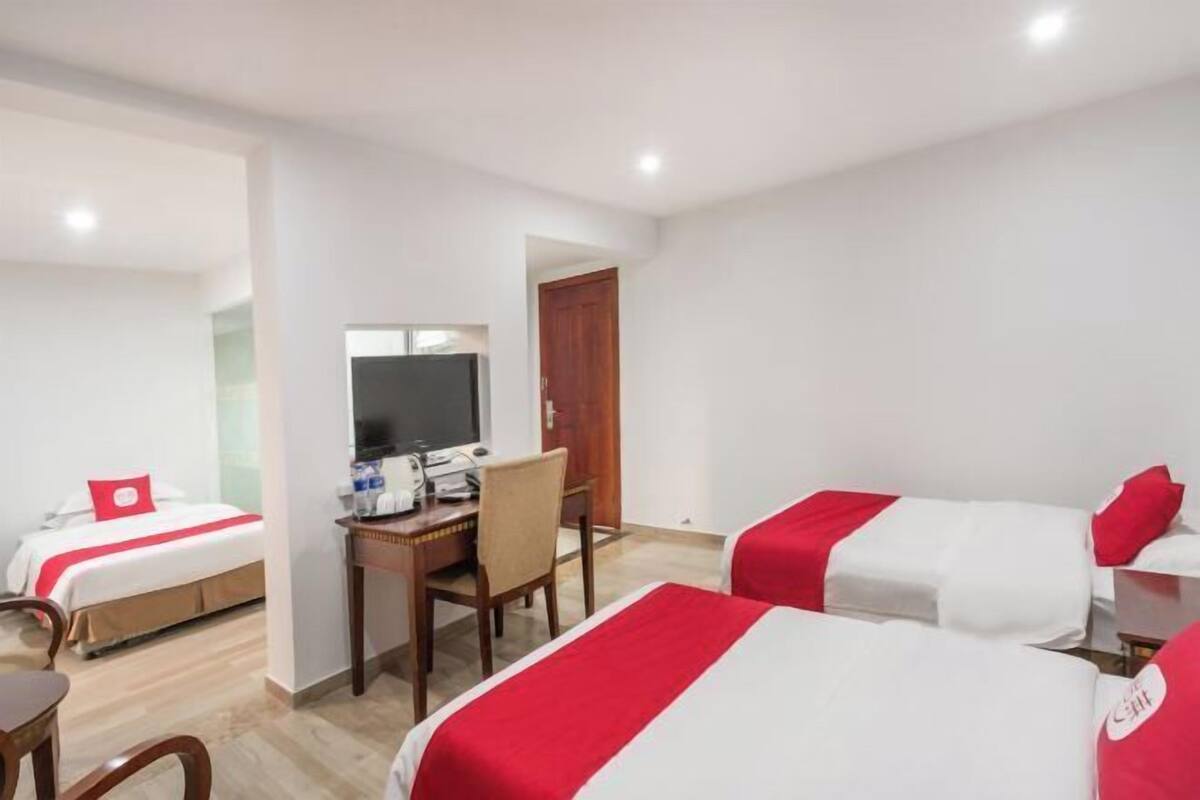 Een hotelkamer met twee bedden, een bureau met een computer en een televisie.