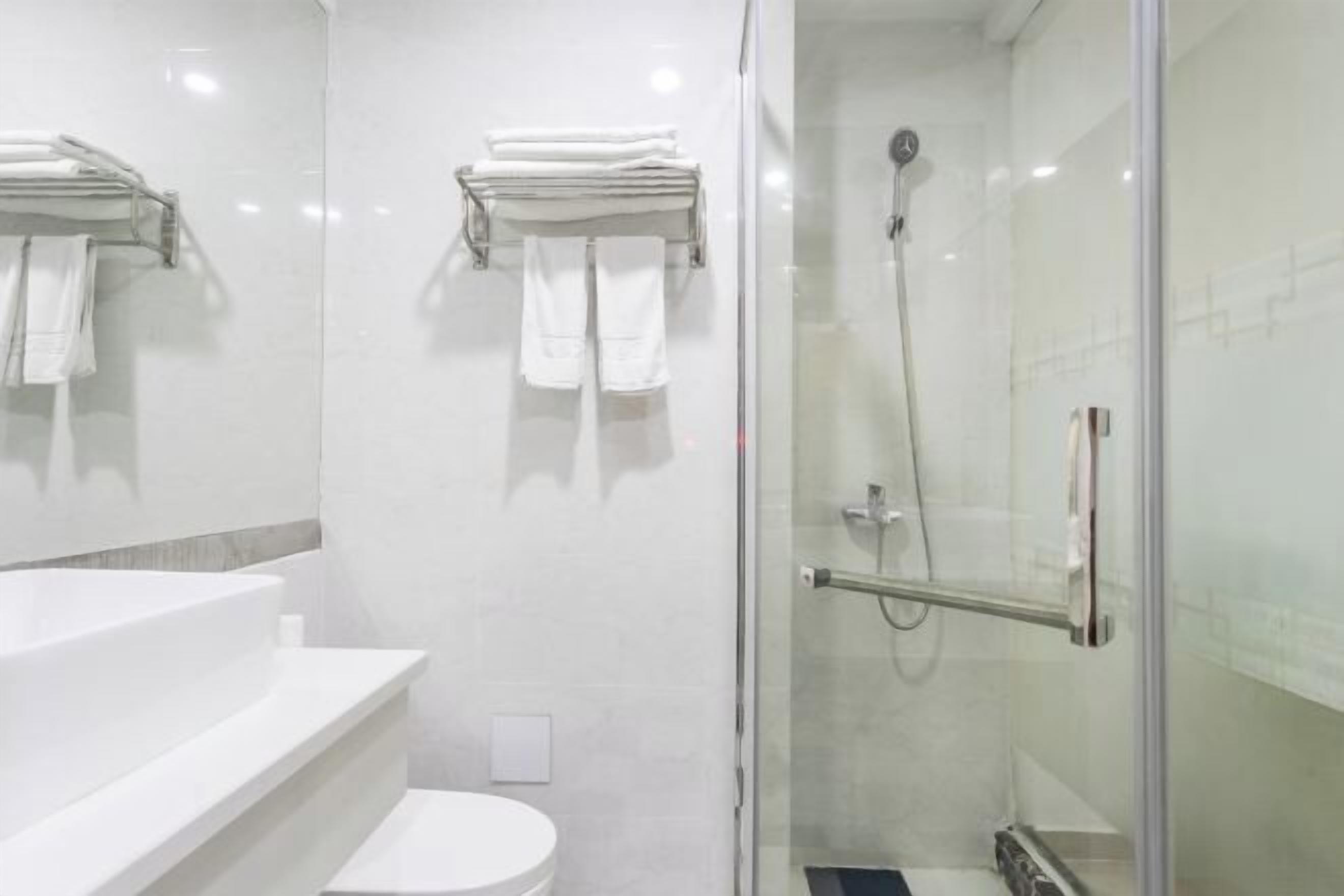 A modern bathroom with a glass-enclosed shower, a white sink, and a toilet.