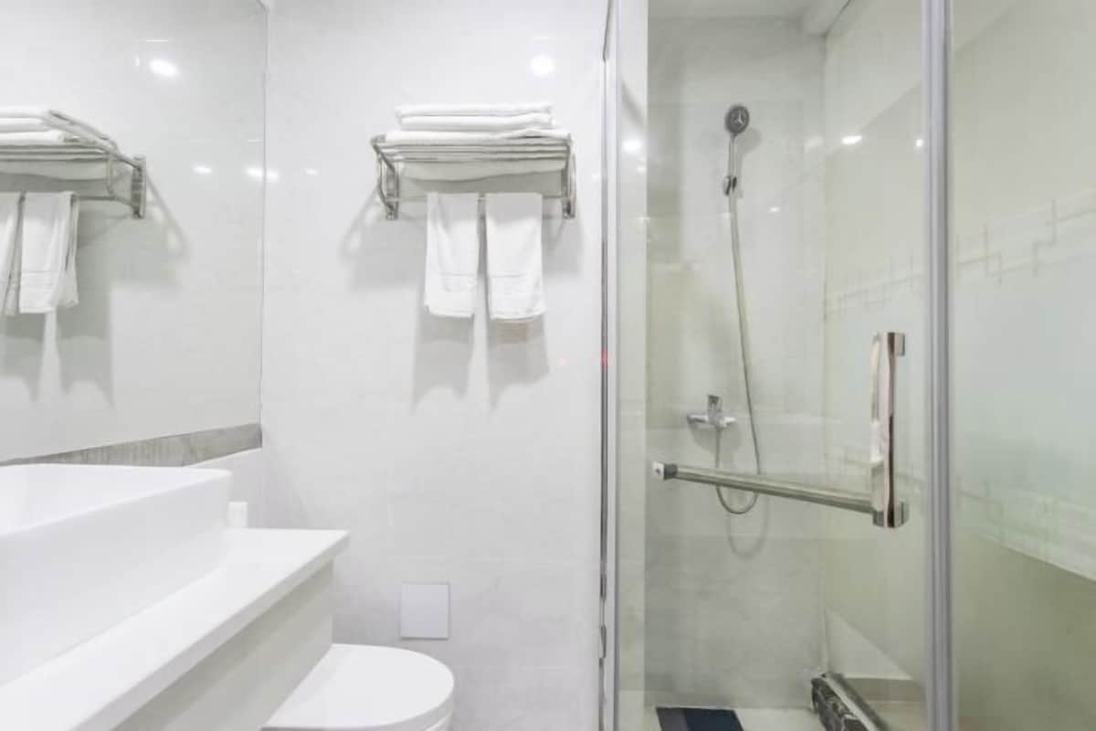 Une salle de bain moderne avec une douche à parois de verre, un lavabo blanc et des toilettes.