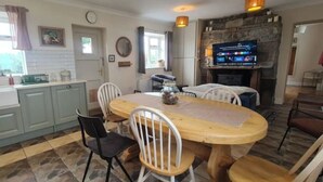 Une cuisine avec un coin repas, une cheminée en pierre et un téléviseur.