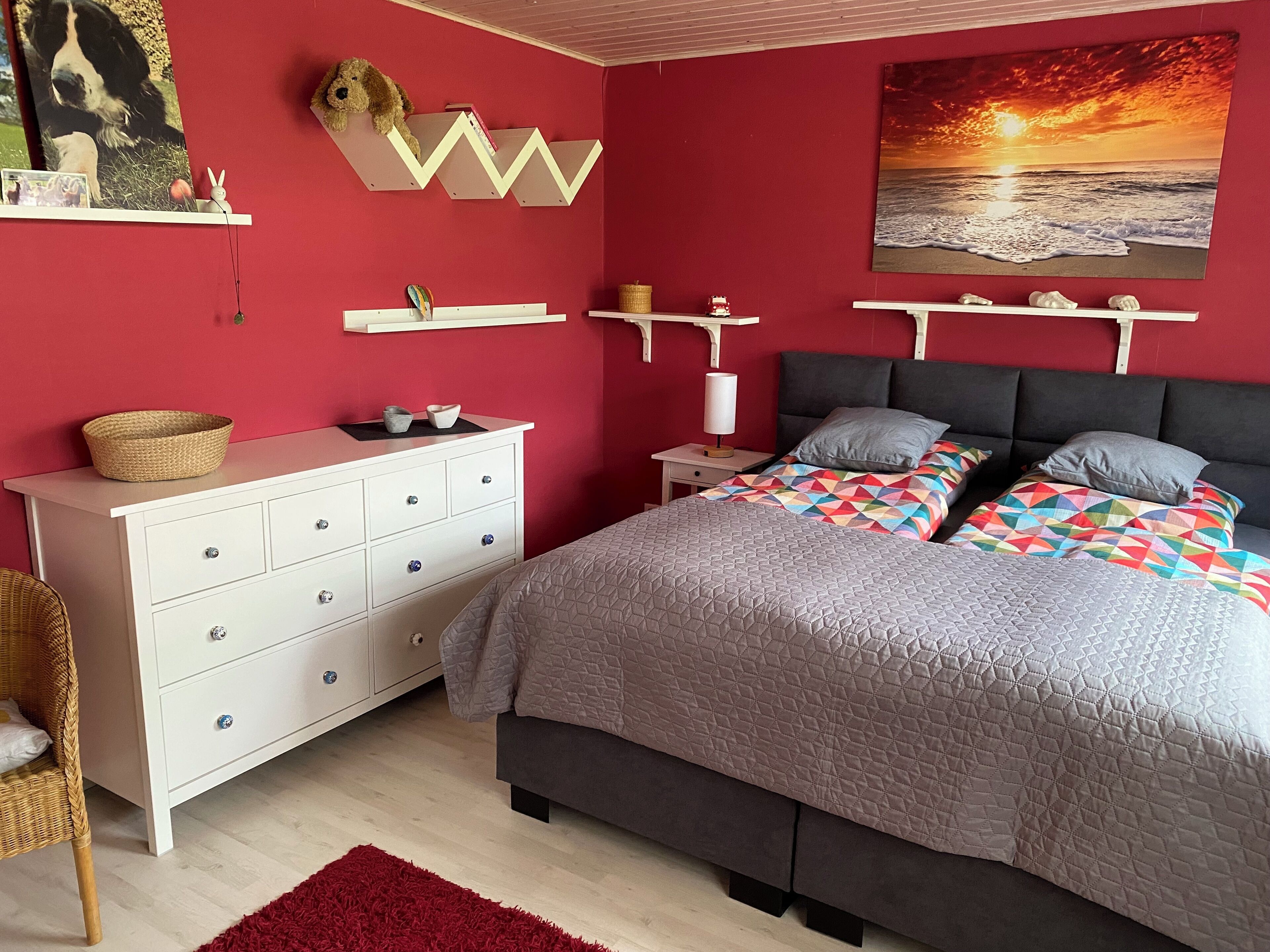 A bedroom with a bed, dresser, nightstand, and wall art.