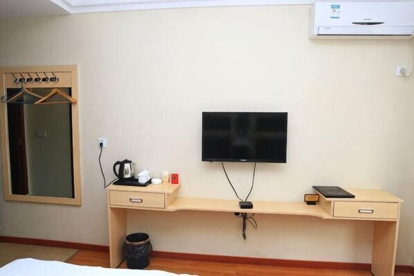 Ein Zimmer mit einem Bett, einem Schreibtisch, einem Fernseher, einem Spiegel und einem Kleiderschrank.