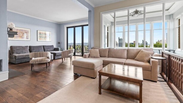 A spacious living room with a large sectional sofa, a coffee table, and a view of the city through large windows.