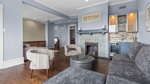 A spacious living room with a fireplace, a dining area, and a kitchen in the background.