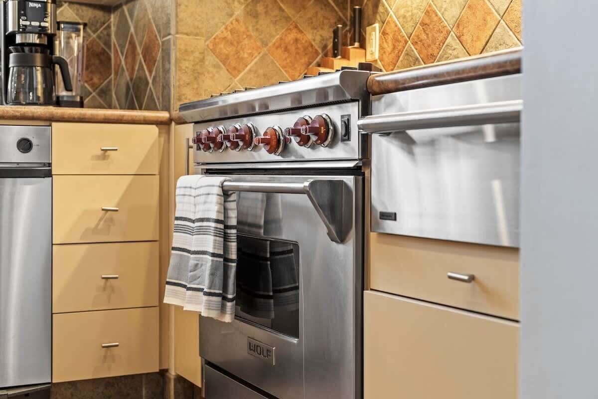A kitchen with a stainless steel stove, oven, and a coffee maker on the countertop.
