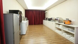 A kitchen with a refrigerator, microwave, and stove, wooden flooring, and a red curtain. - Tianhai Yuyuan Hotel (Jiujiang Railway Station) (Jiujiang)