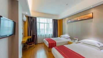 A hotel room with two beds, a desk, a chair, a TV, and a painting on the wall.