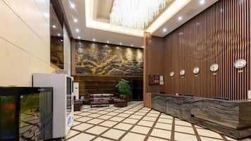 A hotel lobby with a reception desk, seating area, and a decorative wall.