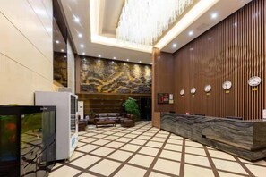 A hotel lobby with a reception desk, seating area, and a decorative wall. - Tianhai Yuyuan Hotel (Jiujiang Railway Station) (Jiujiang)