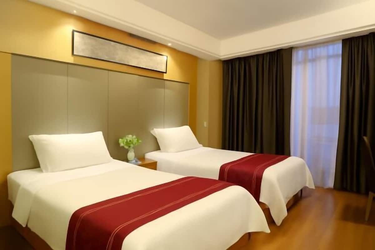 A hotel room with two beds, a large artwork above the beds, and a view of the outside through a window with curtains.