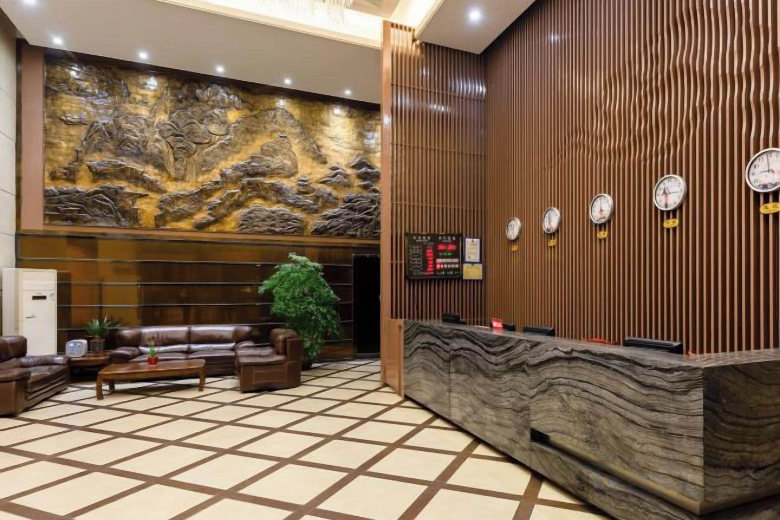 A hotel lobby with a reception desk, seating area, and a large decorative wall.