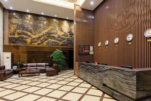 A hotel lobby with a reception desk, seating area, and a large decorative wall. - Tianhai Yuyuan Hotel (Jiujiang Railway Station) (Jiujiang)