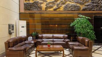 A lobby with leather sofas, a coffee table, a potted plant, and a decorative wall.