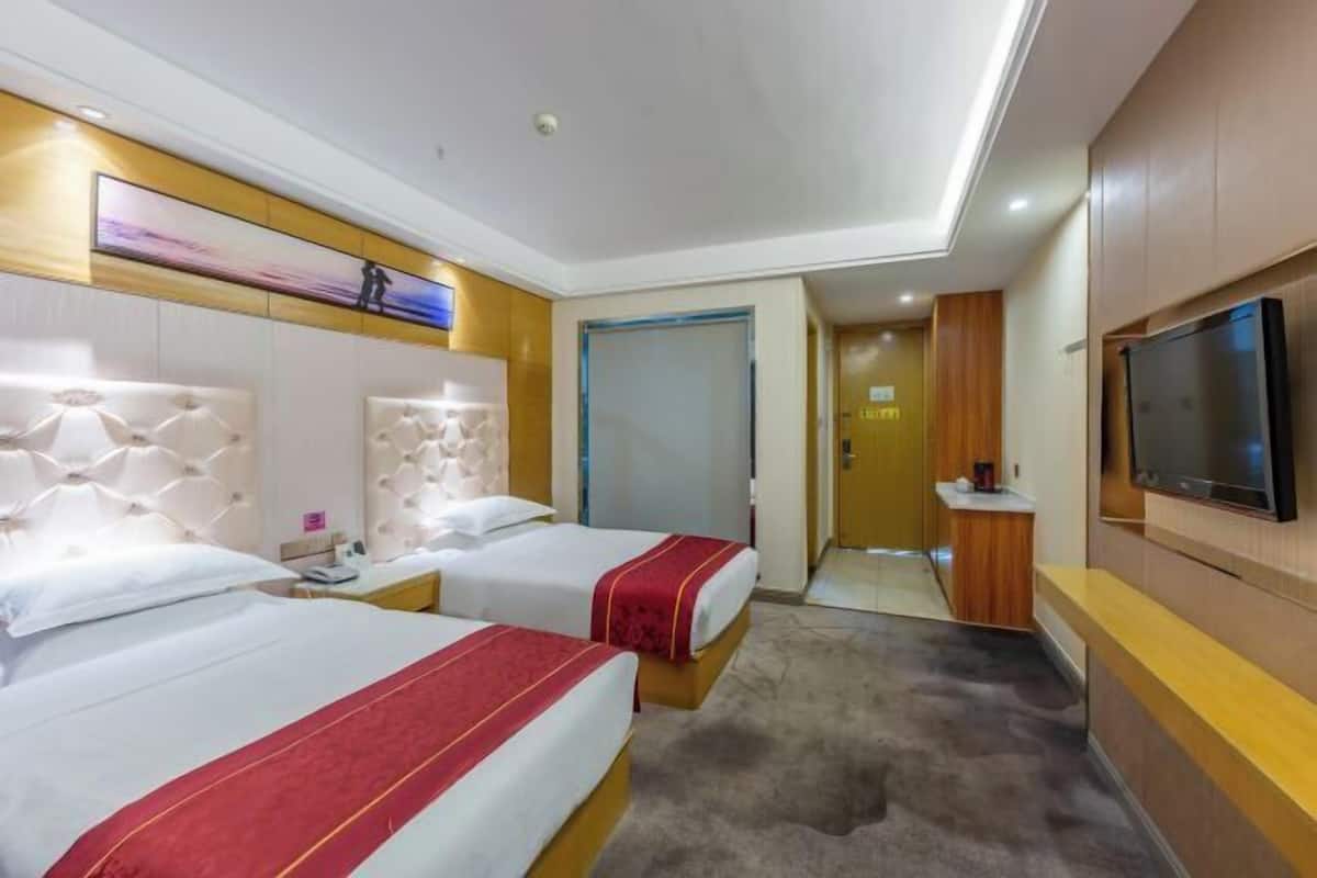 A hotel room with two beds, a TV, and a bathroom door.