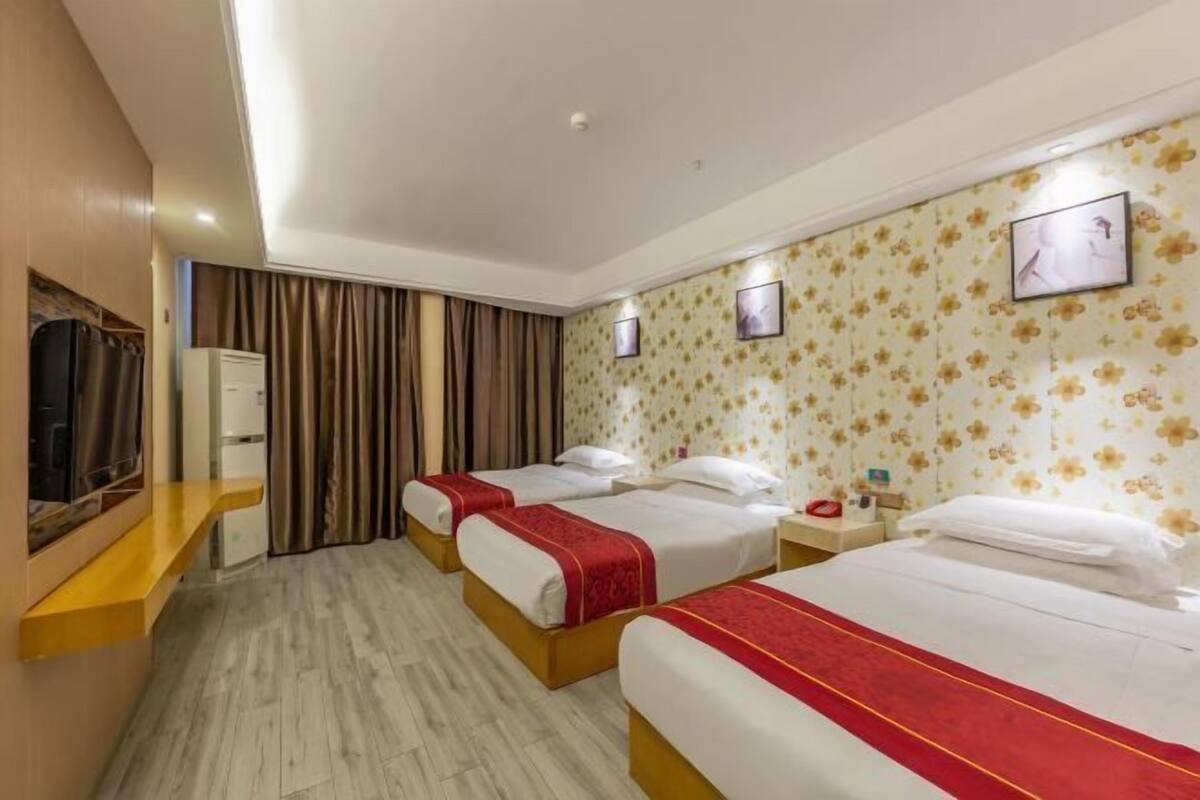 A hotel room with two beds, a flat-screen TV, a desk with a chair, and a wardrobe.