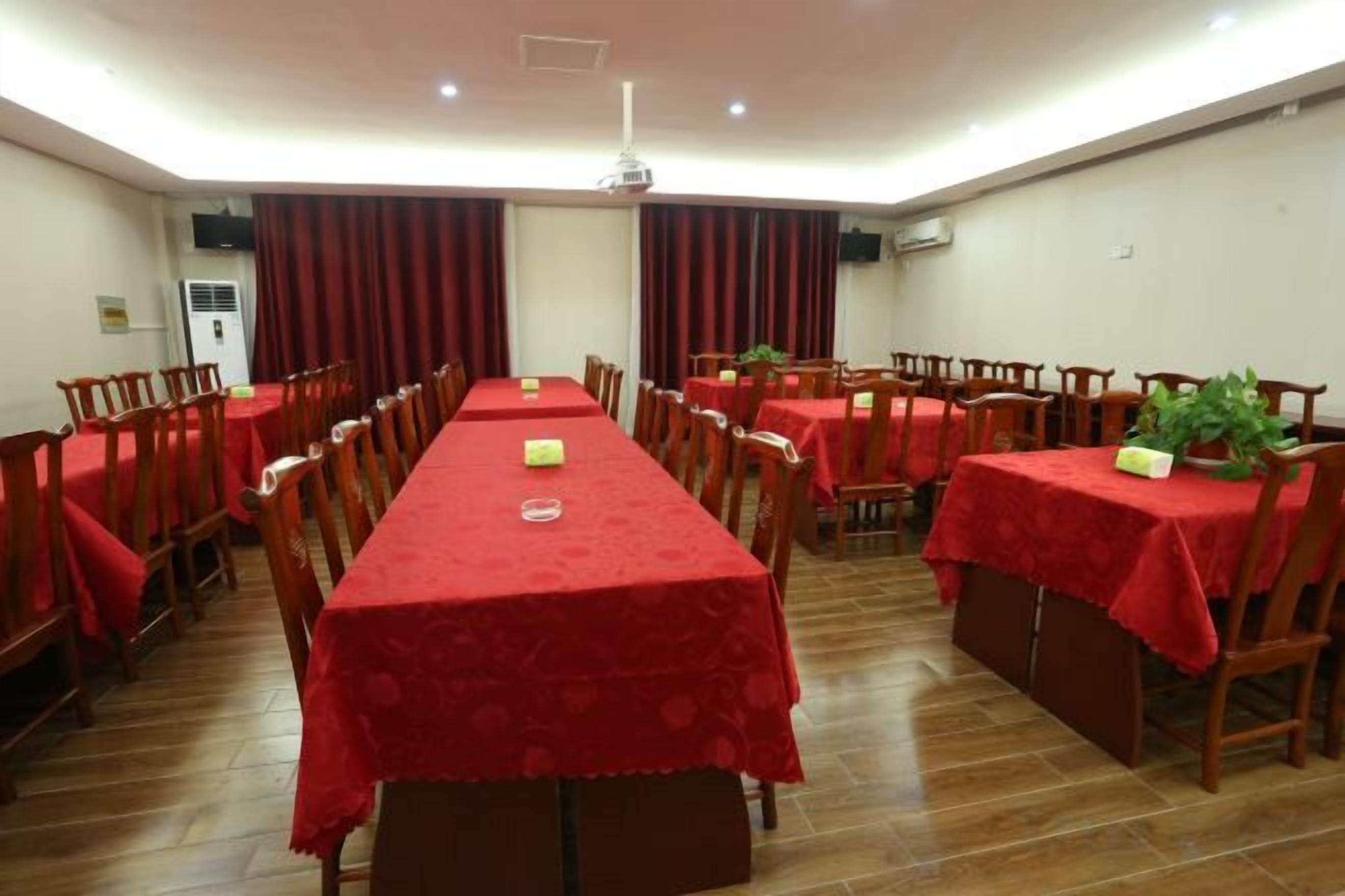 A conference room with a long table, multiple chairs, and red tablecloths.