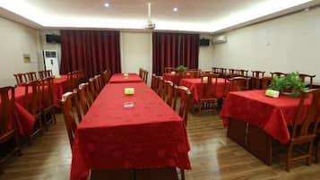 A conference room with a long table, multiple chairs, and red tablecloths.