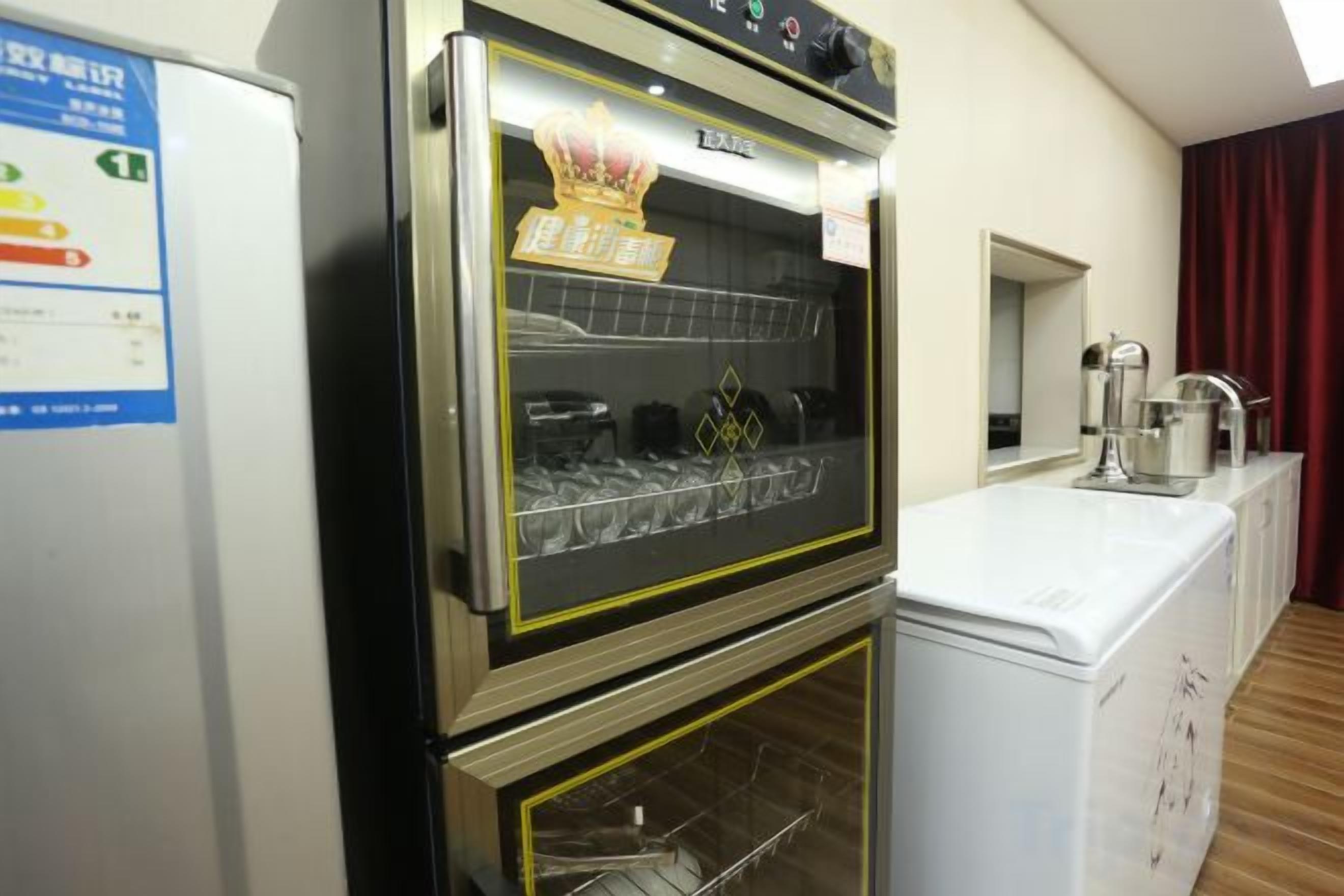 A kitchen with a built-in oven and microwave, a refrigerator, and a window with curtains.