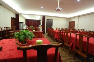 Comedor con mesas cubiertas con manteles rojos, sillas de madera y una planta en maceta.