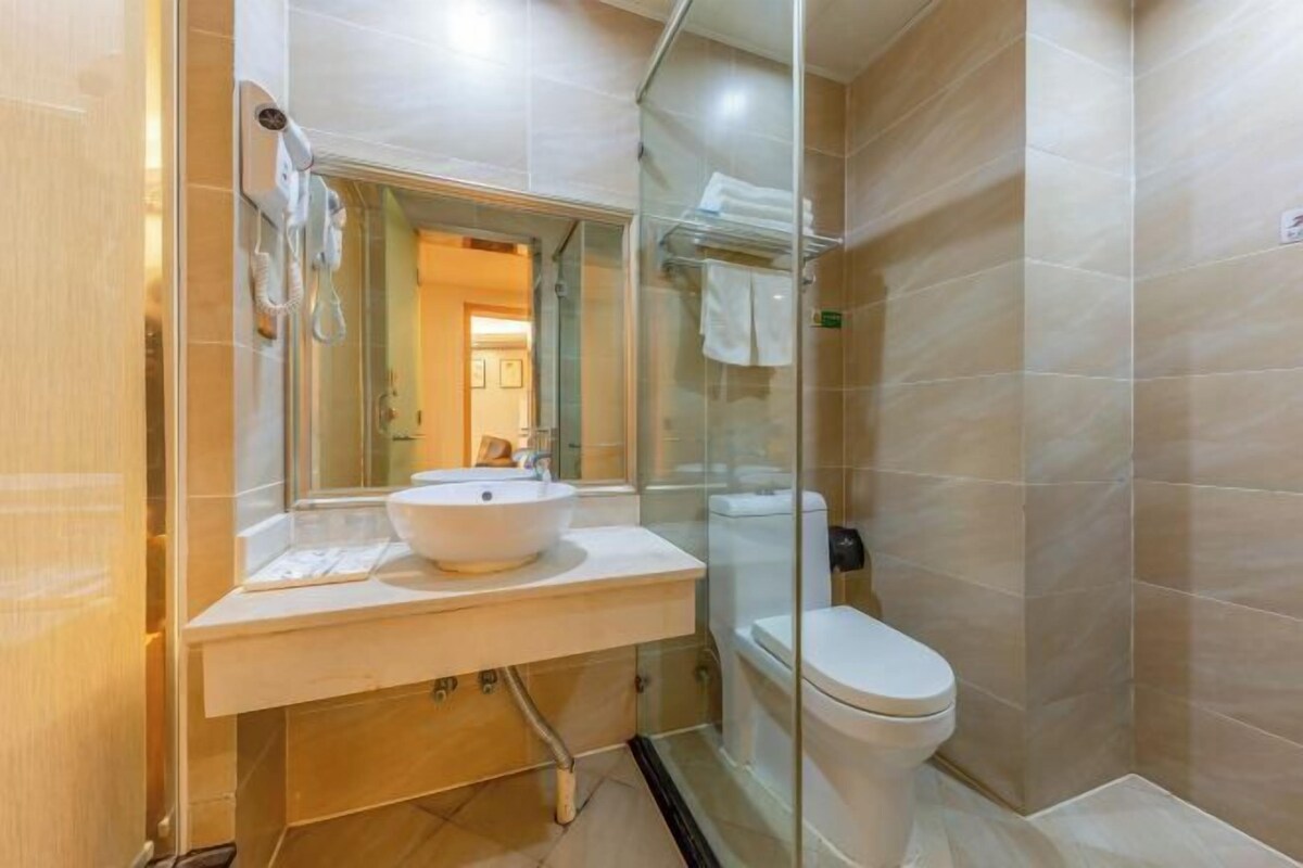 Un baño moderno con cabina de ducha de vidrio, un lavabo blanco y un inodoro.