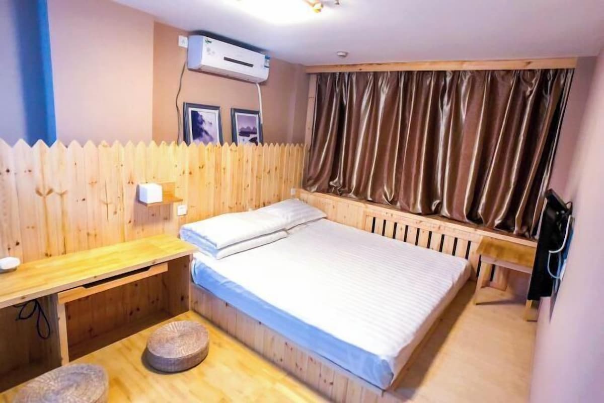 Une petite pièce agréable, avec un lit en bois, un bureau, une chaise et une fenêtre avec des rideaux.