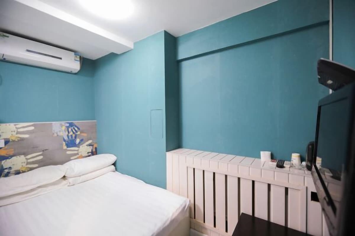 Une chambre à coucher avec un lit, une tête de lit blanche et un radiateur blanc.