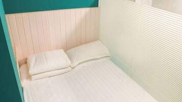 A single bed with white bedding in a room with teal and white walls.