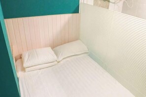 A single bed with white bedding in a room with teal and white walls.
