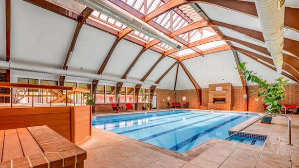An indoor swimming pool with a high ceiling and brick walls, surrounded by seating areas and potted plants. - Mountain Dream in Adorable Frisco - 5 Ski Resorts and Lake Dillon (Frisco)