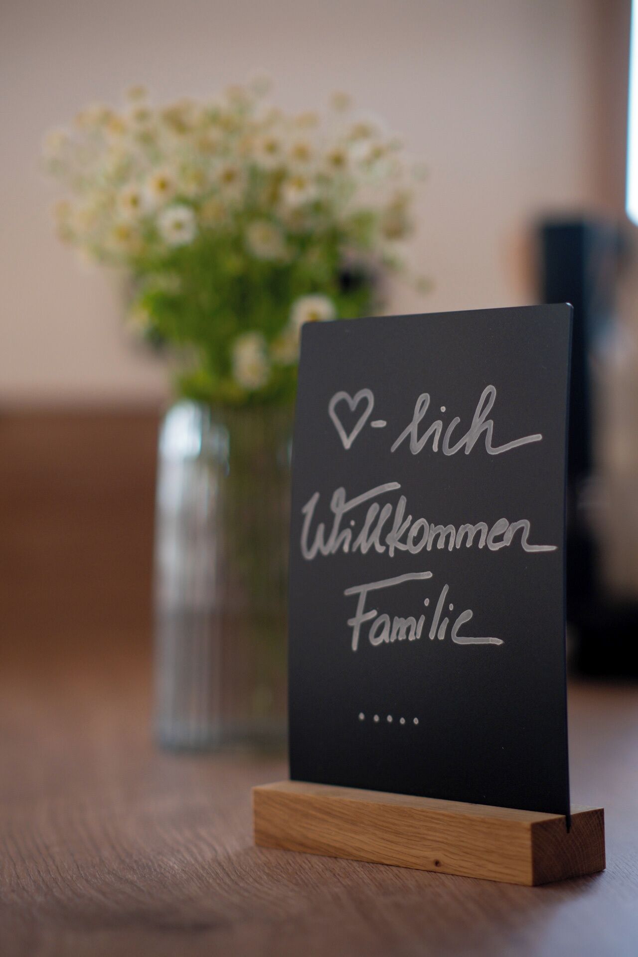 Eine Tafel mit der Aufschrift "Willkommen Familie", auf einem hölzernen Ständer platziert.