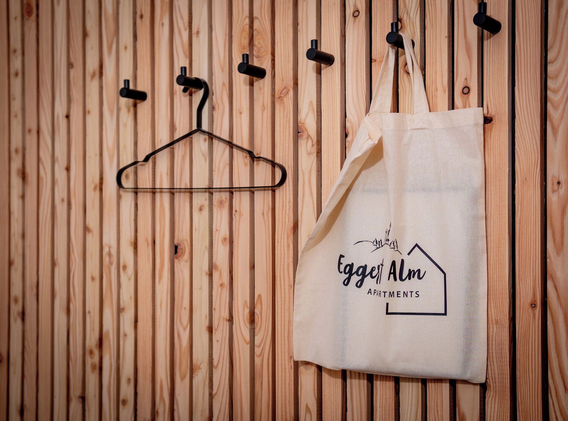 Un mur en bois avec un sac en tissu suspendu et un cintre.