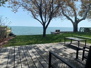 A wooden deck with a table and chairs, a grassy area with a tree, and a view of the sea. - "Hook, Line,& Sinker"- At the edge of Erie; 7 days stay plus 1 chartering free
(Kingsville)