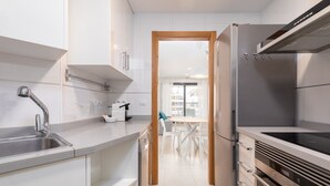 Een moderne keuken met roestvrijstalen apparatuur, witte keukenkastjes en een deurpost van hout die leidt naar een eethoek.
